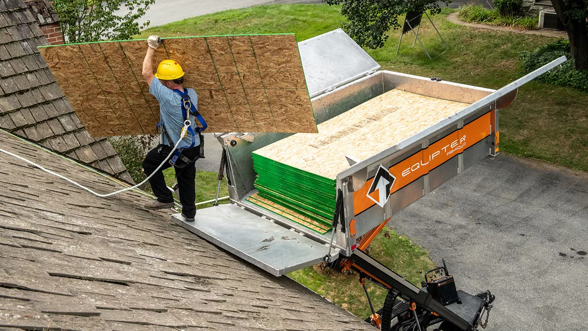 Roofer on a roof using RB4000 at a job site to get wood panels to the roof