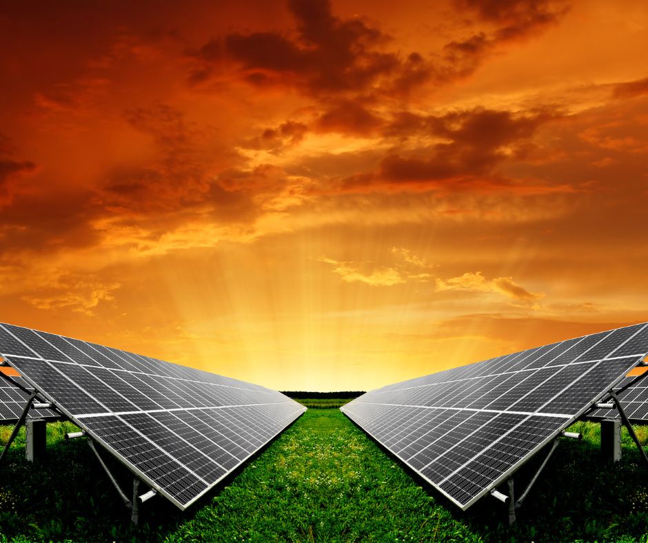 sunset over two solar panels in a green field