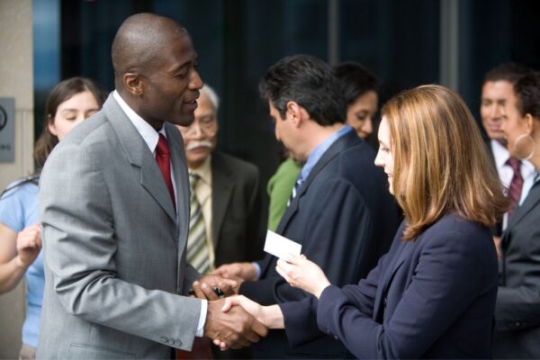 Man giving his business card to a woman at a networking event