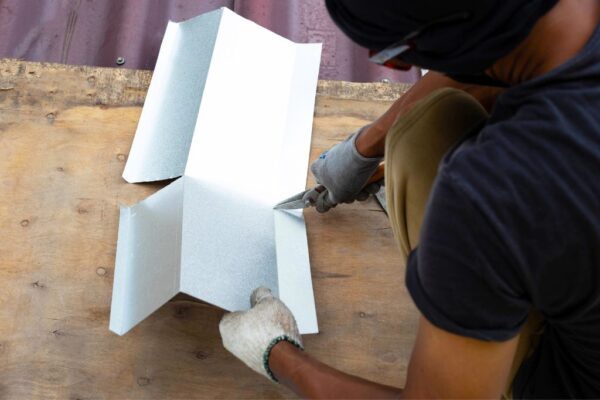 Roofing contractor cutting a sheet of metal for a roofing repair