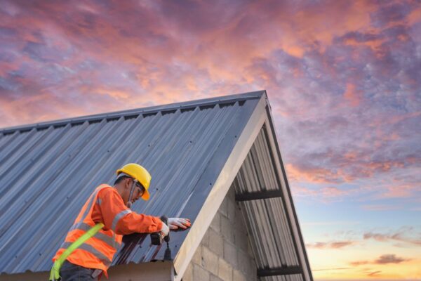 Roofing contractor working on a metal roof at sunset