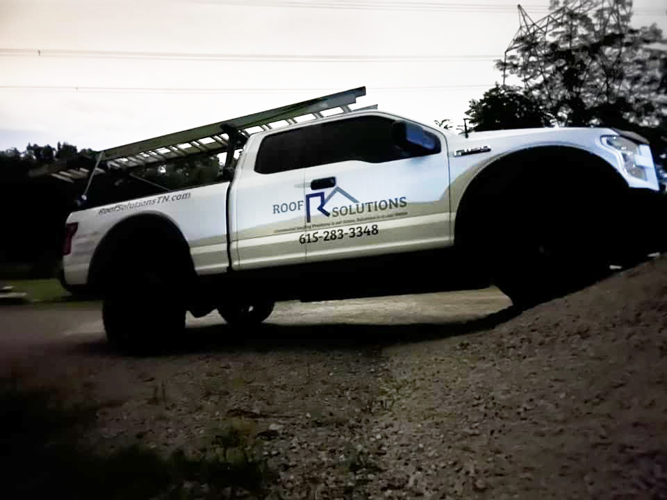 White and blue roofing truck wrap for Roof Solutions